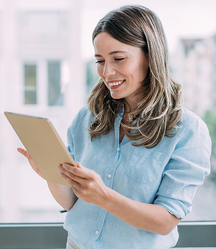 A small business owner holds up a tablet while smiling and looking at the screen.