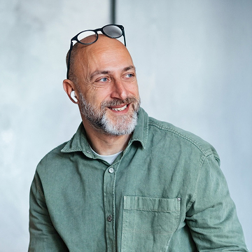 A happy business owner with glasses on the top of his head looks to the left.